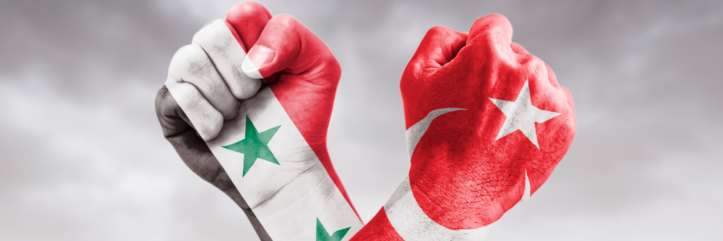 Flags of Turkey and Syria painted on two clenched cross-fists on black background / tense relationship between Turkey and Syria concept